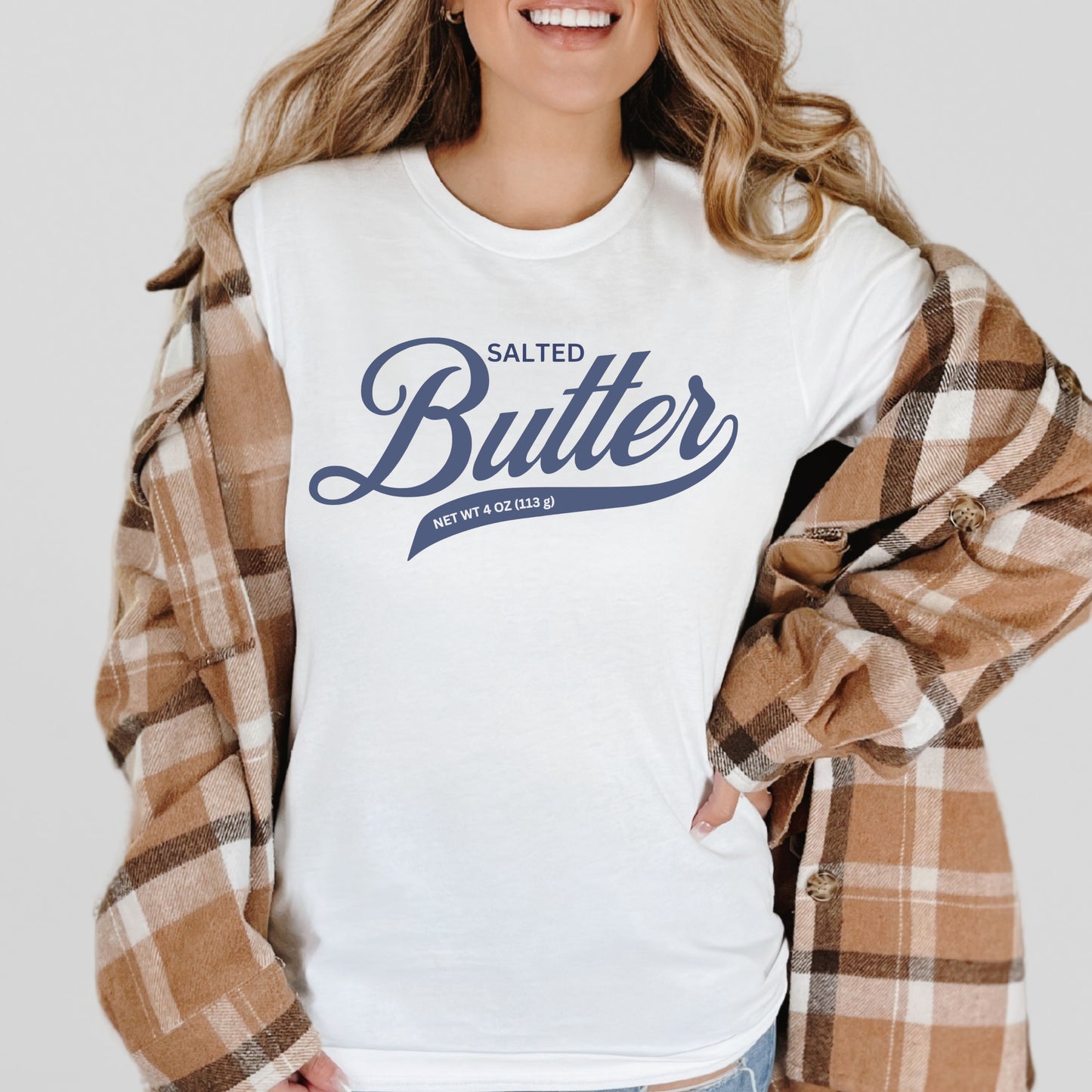 White butter script t shirt layered with flannel for casual outfit styling. Comfortable graphic tee with clean script design for everyday wear.