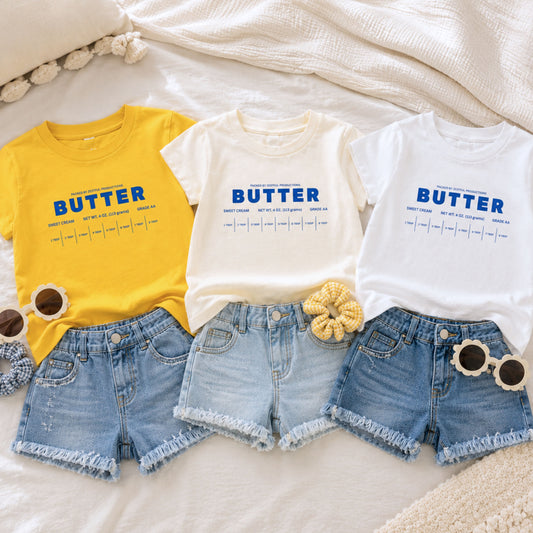 Butter toddler shirts in yellow white and cream color options styled with denim shorts for boutique kids fashion. Retro foodie toddler tees inspired by sweet cream baking themes, birthday outfits, and preschool apparel.