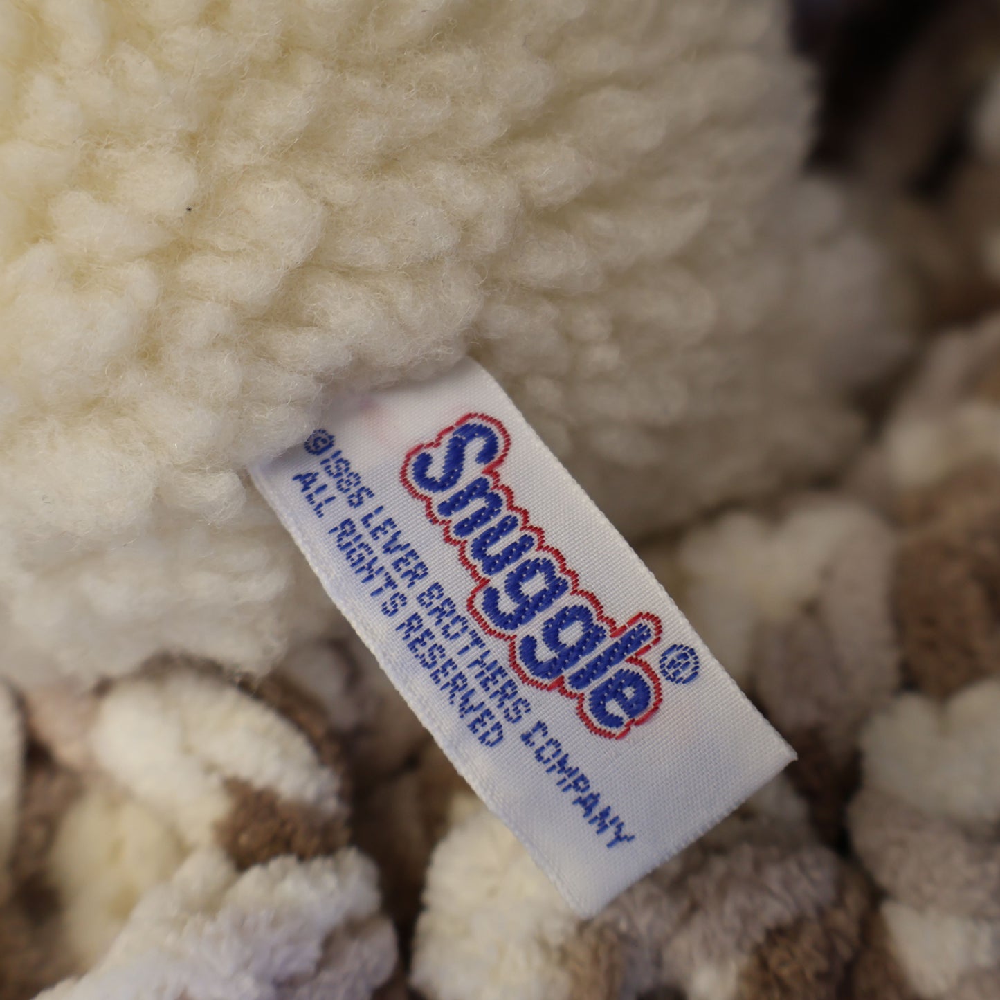 Detailed close-up of the original Snuggle tag showing Lever Brothers branding on an authentic 1986 plush mascot. Original tags enhance collector appeal for vintage advertising enthusiasts and lovers of nostalgic household memorabilia.