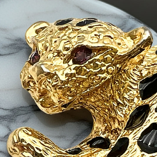 Close-up of rhinestone eyes and black enamel spots on cheetah brooch