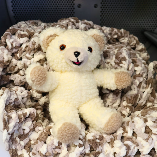 Vintage Snuggle Bear collectible posed on a cozy knit blanket, showcasing its soft cream plush, smiling face, and timeless 1990s charm. This Lever Brothers advertising mascot is perfect for laundry room decor, farmhouse styling, nursery shelves, or childhood nostalgia collections.