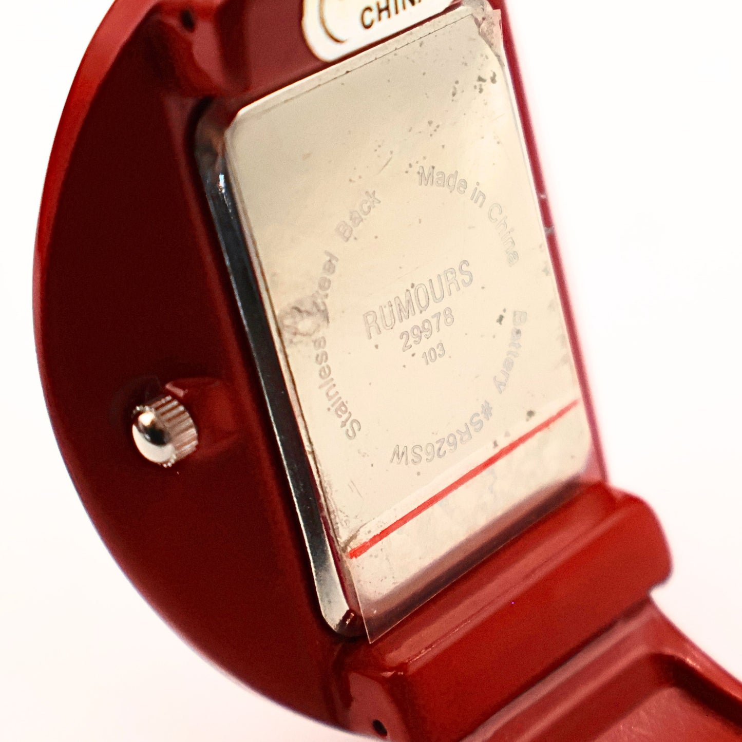 Close-up detail of Rumours 29978 watch stamp on back case, vintage red cuff watch with model number and branding visible on metal plate