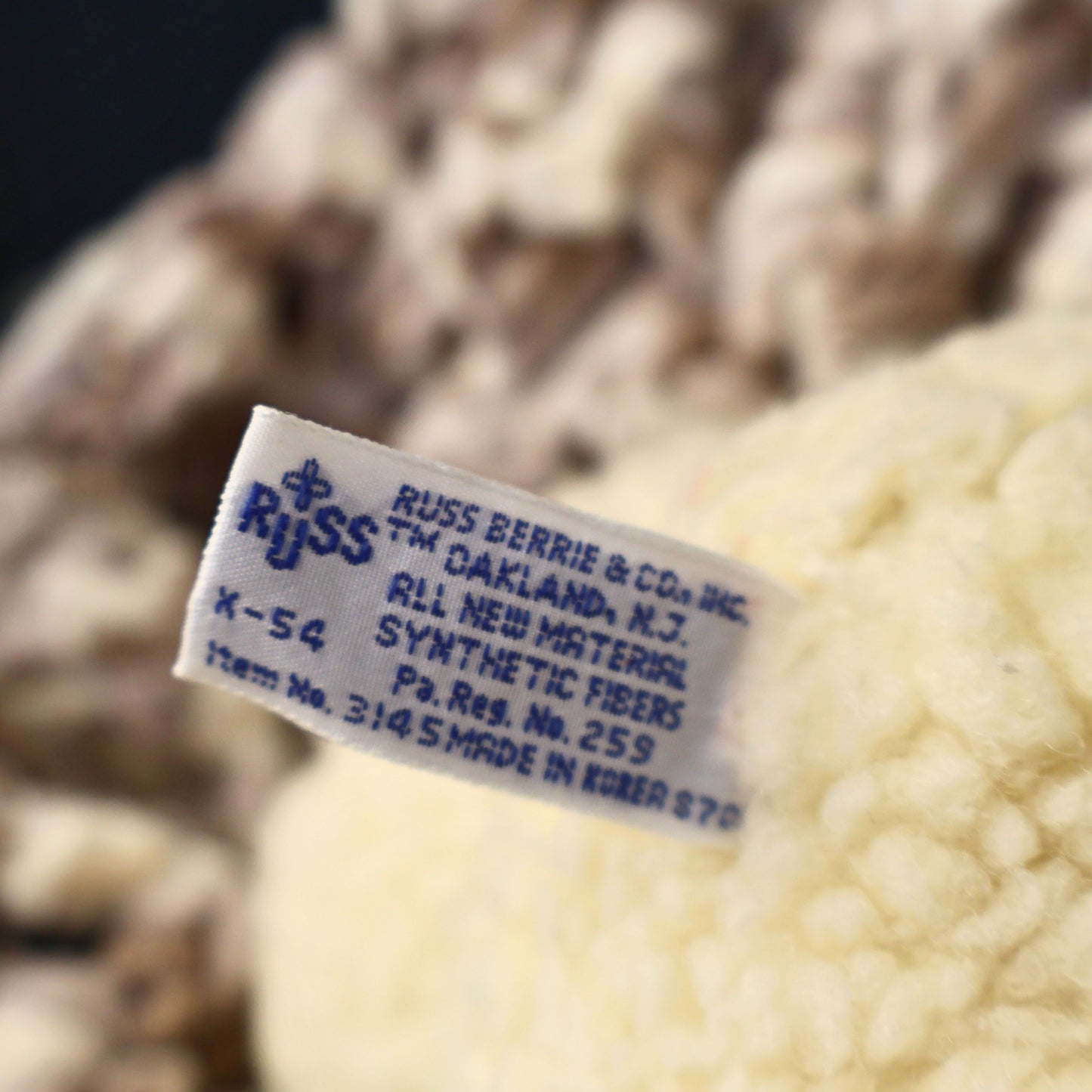 Close-up photograph of the original Russ Berrie & Co. manufacturer tag on an authentic 1986 Snuggle Bear plush by Lever Brothers. The intact production label adds collector appeal for buyers seeking genuine vintage advertising and plush collectibles.