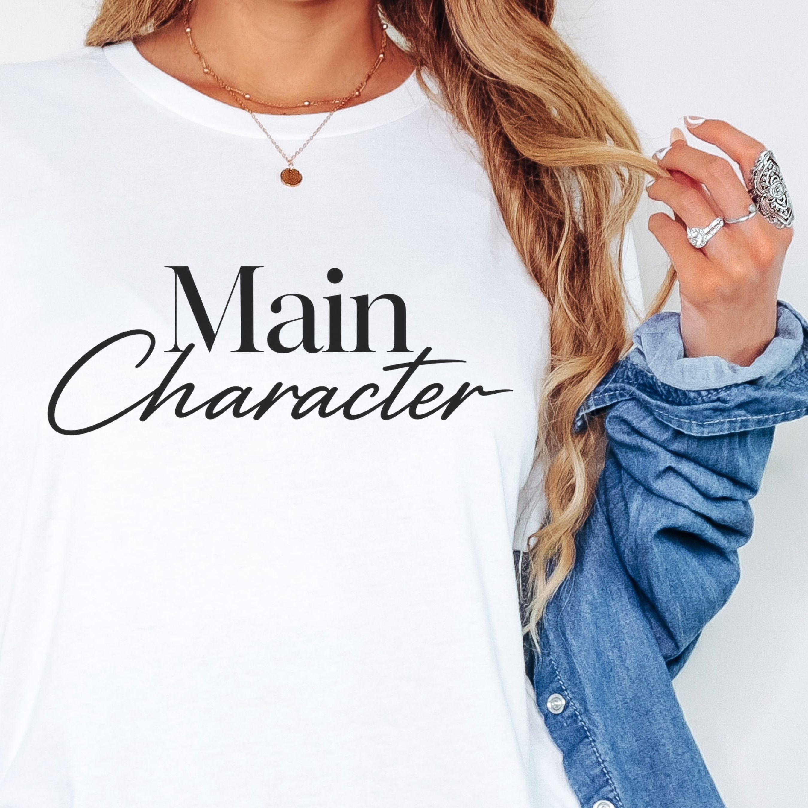 woman wearing white t-shirt with Main Character graphic styled with denim shirt and layered necklaces casual everyday outfit women’s essentials clothing