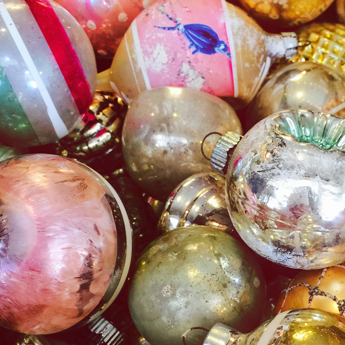 Close-up of vintage glass Christmas ornaments in gold, pink, and metallic tones, showcasing retro holiday decor and nostalgic seasonal styling