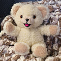 Authentic 1986 Snuggle fabric softener mascot plush with fluffy cream sherpa fur and smiling face. This vintage Lever Brothers advertising collectible is displayed seated on a cozy blanket and makes charming laundry room decor or a nostalgic collector's display piece.