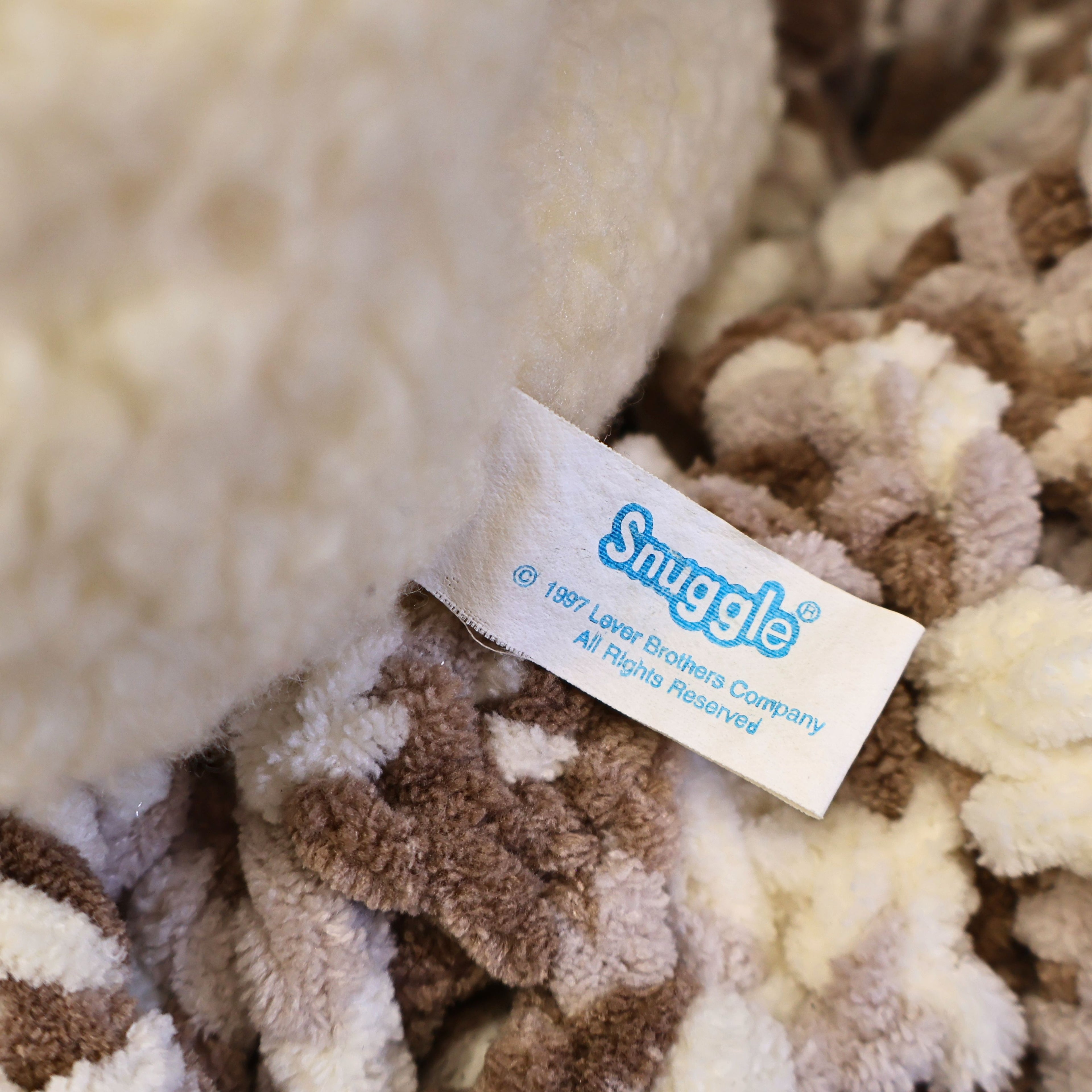 Close-up of the original sewn Snuggle tag showing ©1997 Lever Brothers Company, confirming authenticity for collectors. The intact manufacturer label adds value to this vintage advertising mascot, nostalgic plush toy, and laundry room collectible.