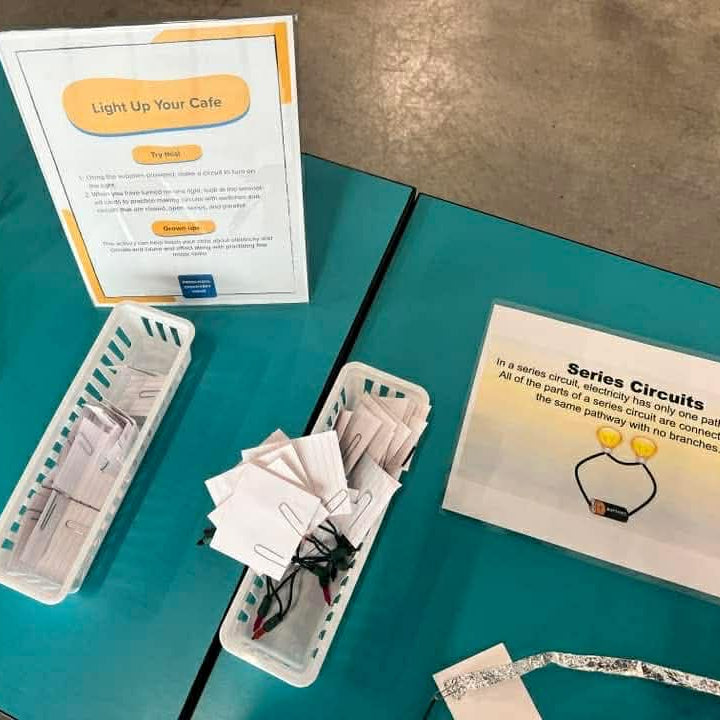 Science education materials on a teal table with printed cards and components.