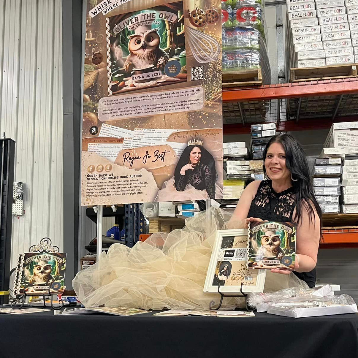 Woman at a convention table with promotional materials and a banner in the background