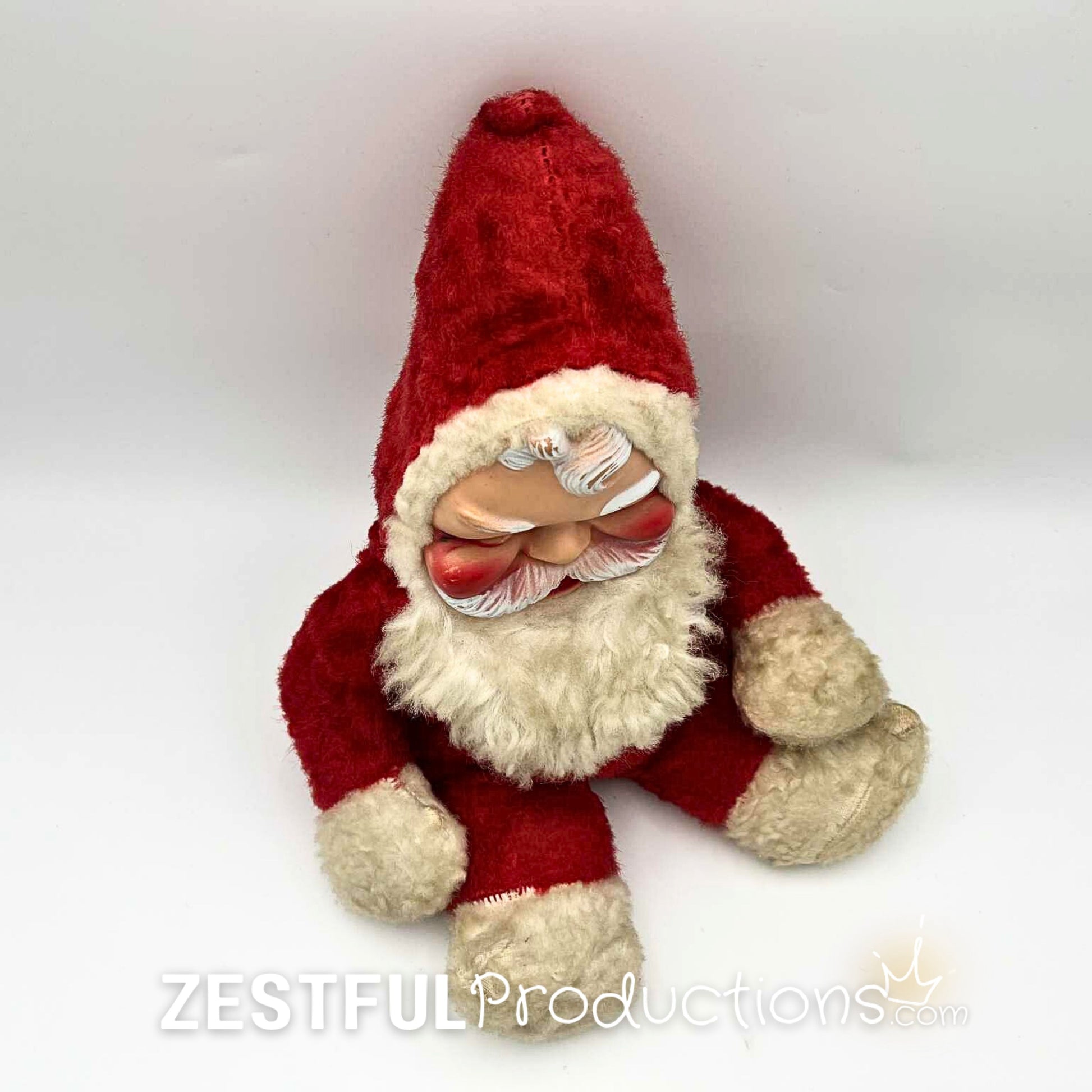 Overhead view of vintage Santa Claus plush doll collectible in red suit with fluffy beard and molded face. Rushton style 1950s Christmas decor piece perfect for retro holiday decorating and antique toy collections.
