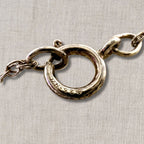 macro detail of 925 stamped sterling silver clasp on vintage necklace chain, hallmark verification for authentic silver jewelry, close up texture and patina on spring ring closure for coin pendant necklace