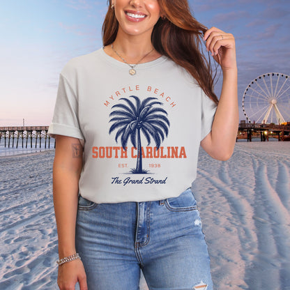 Person wearing a t-shirt with 'Myrtle Beach, South Carolina' design on a beach with a Ferris wheel in the background.