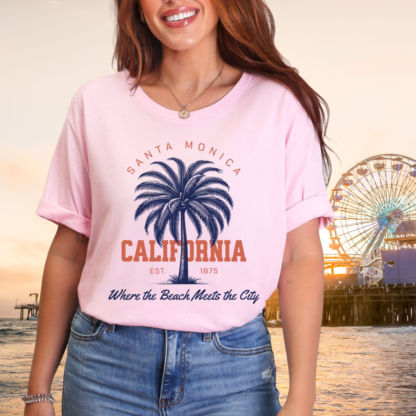 Person wearing a pink t-shirt with Santa Monica California design, ferris wheel in the background