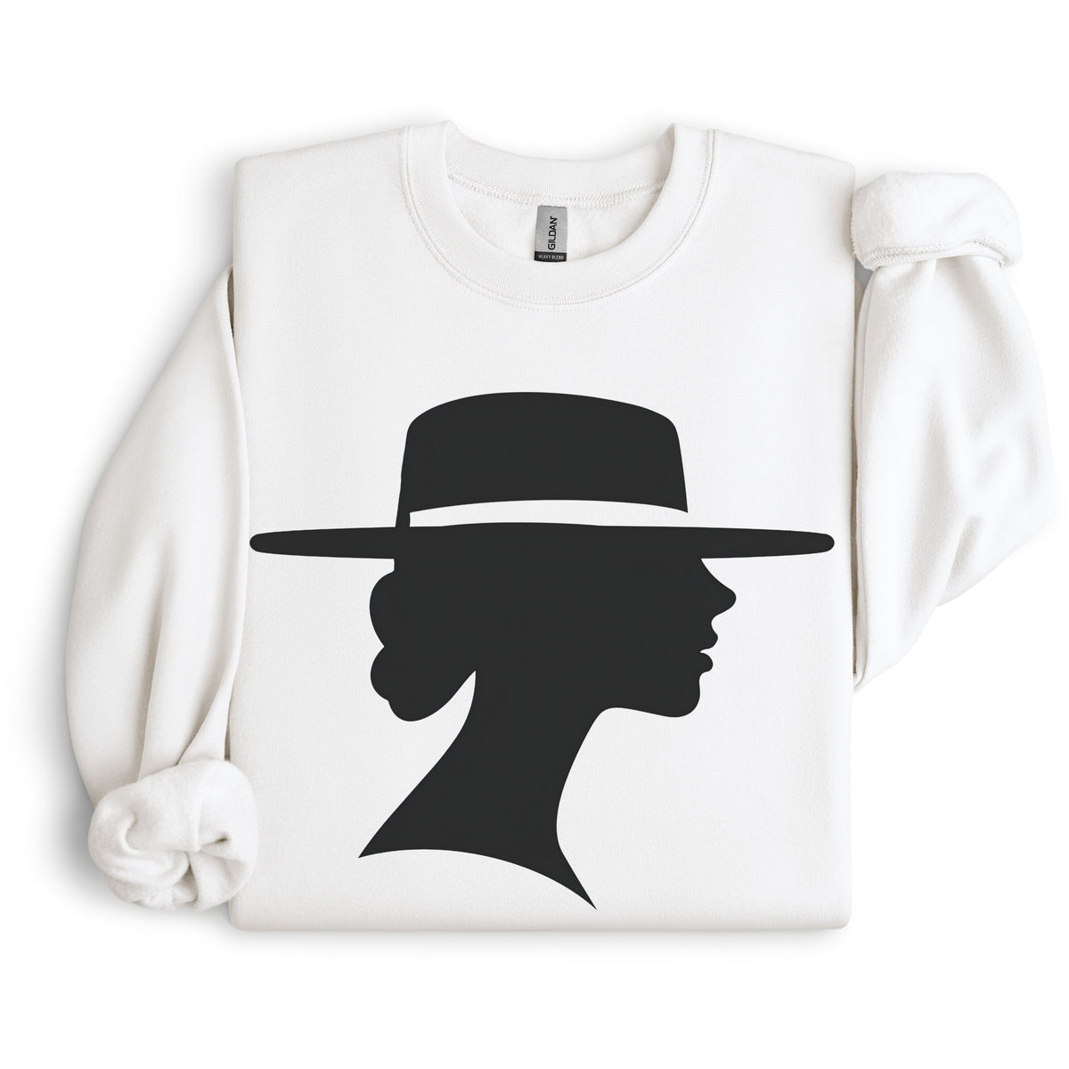 White crewneck sweatshirt arranged flat with folded sleeves, featuring a black silhouette of a woman in side profile beneath a wide-brimmed hat.