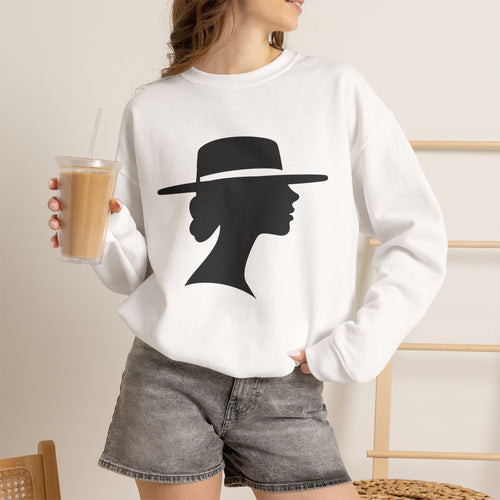 Woman holding a tall iced drink while wearing a white silhouette graphic sweatshirt with gray denim shorts, with one hand tucked into a pocket.