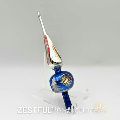 Vintage 1960s mercury glass Christmas tree topper displayed on acrylic stand featuring blue glass body, silver glitter accents, and retro holiday finial styling with original box included.