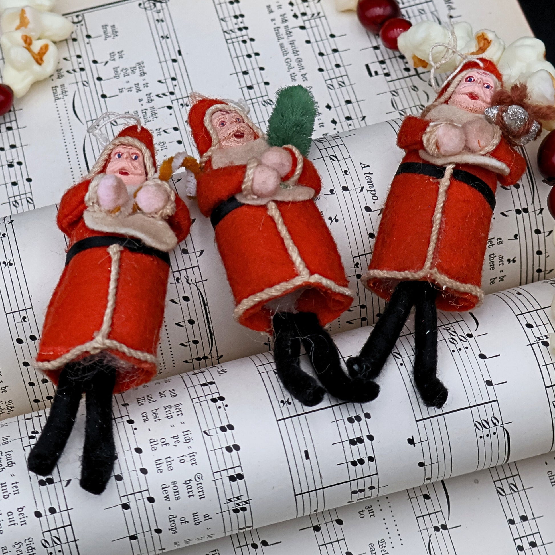 Antique German Belsnickle Santa ornaments displayed on vintage sheet music, styled holiday collectible decor