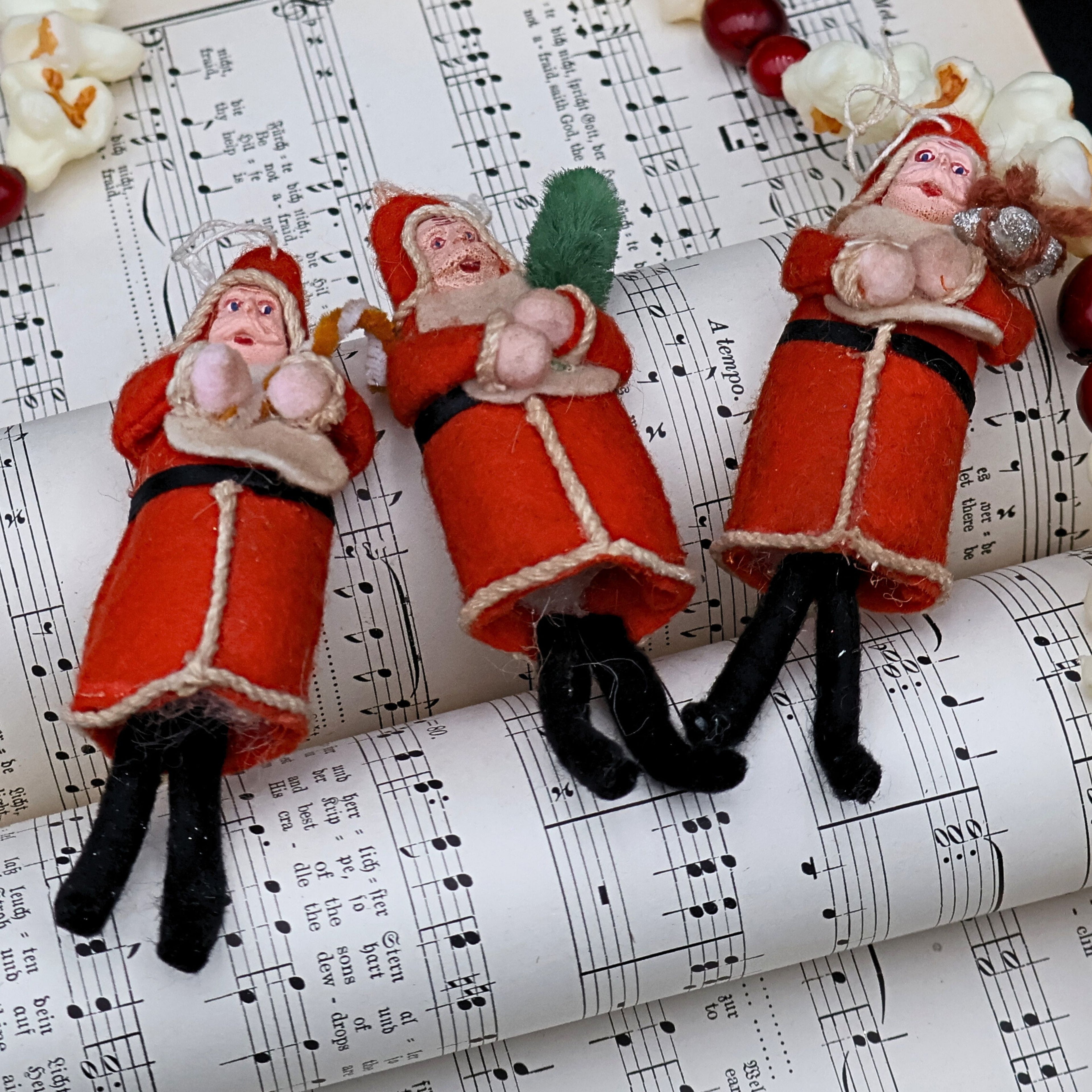 Antique German Belsnickle Santa ornaments displayed on vintage sheet music, styled holiday collectible decor