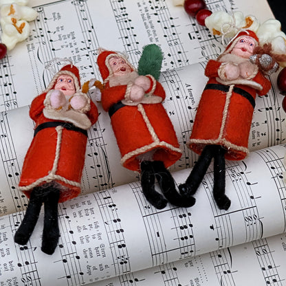 Antique German Belsnickle Santa ornaments displayed on vintage sheet music, styled holiday collectible decor