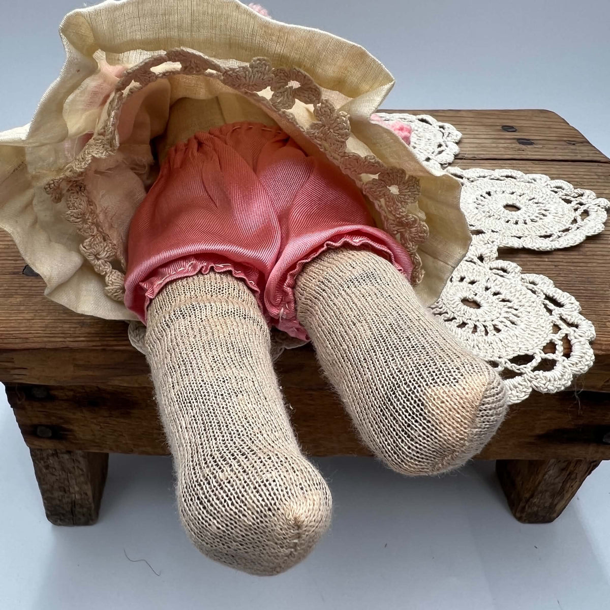 Close-up of both fabric-covered lower legs and feet beneath the lifted skirt, showing their texture, seams, discoloration, and visible wear.