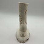 Rear view of a tall vintage Victorian boot vase showing the smooth back of the ceramic shaft, sculpted folds and small heel rising above an ornate pedestal base. Visible finish variations and brown distressed accents contribute to its hand-decorated vintage character.