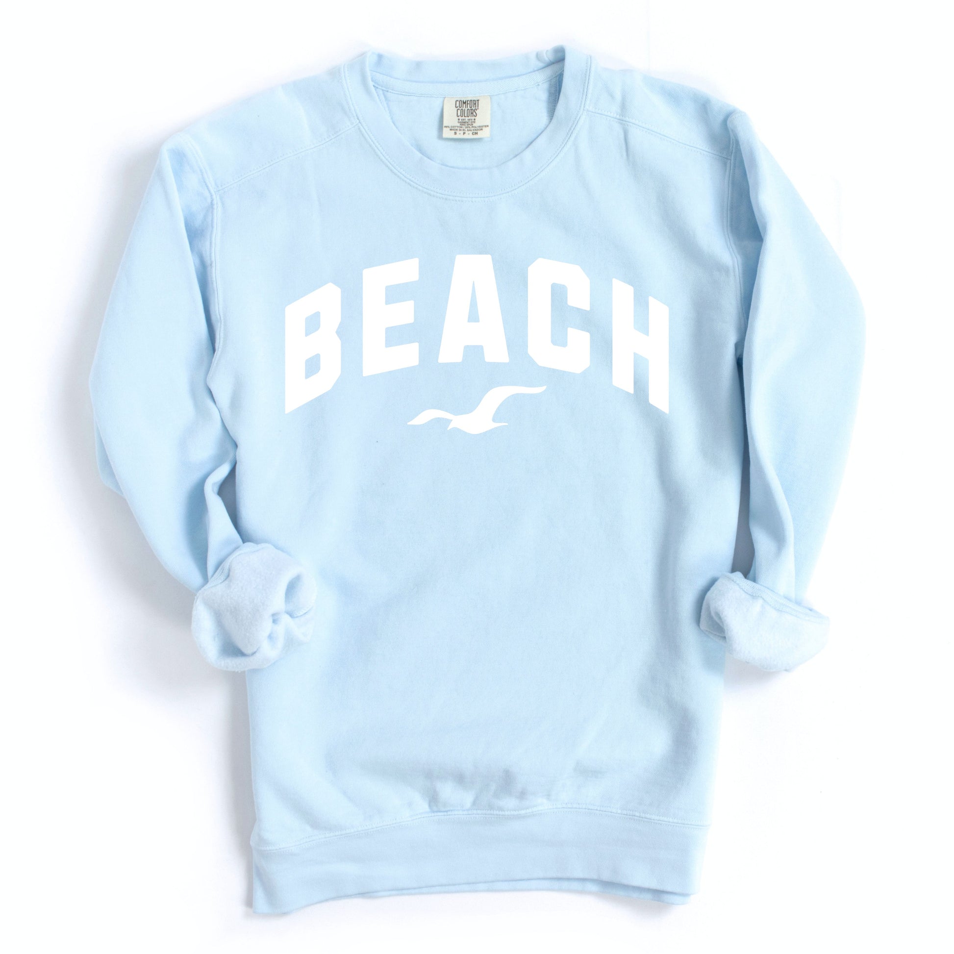 Light blue chambray beach crewneck sweatshirt flat lay, soft oversized fleece pullover with beach graphic, casual coastal outfit sweatshirt