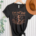 Black western graphic tee hanging with cowboy hat styling, featuring vintage cowgirl design and neutral copper print for a bold boutique look