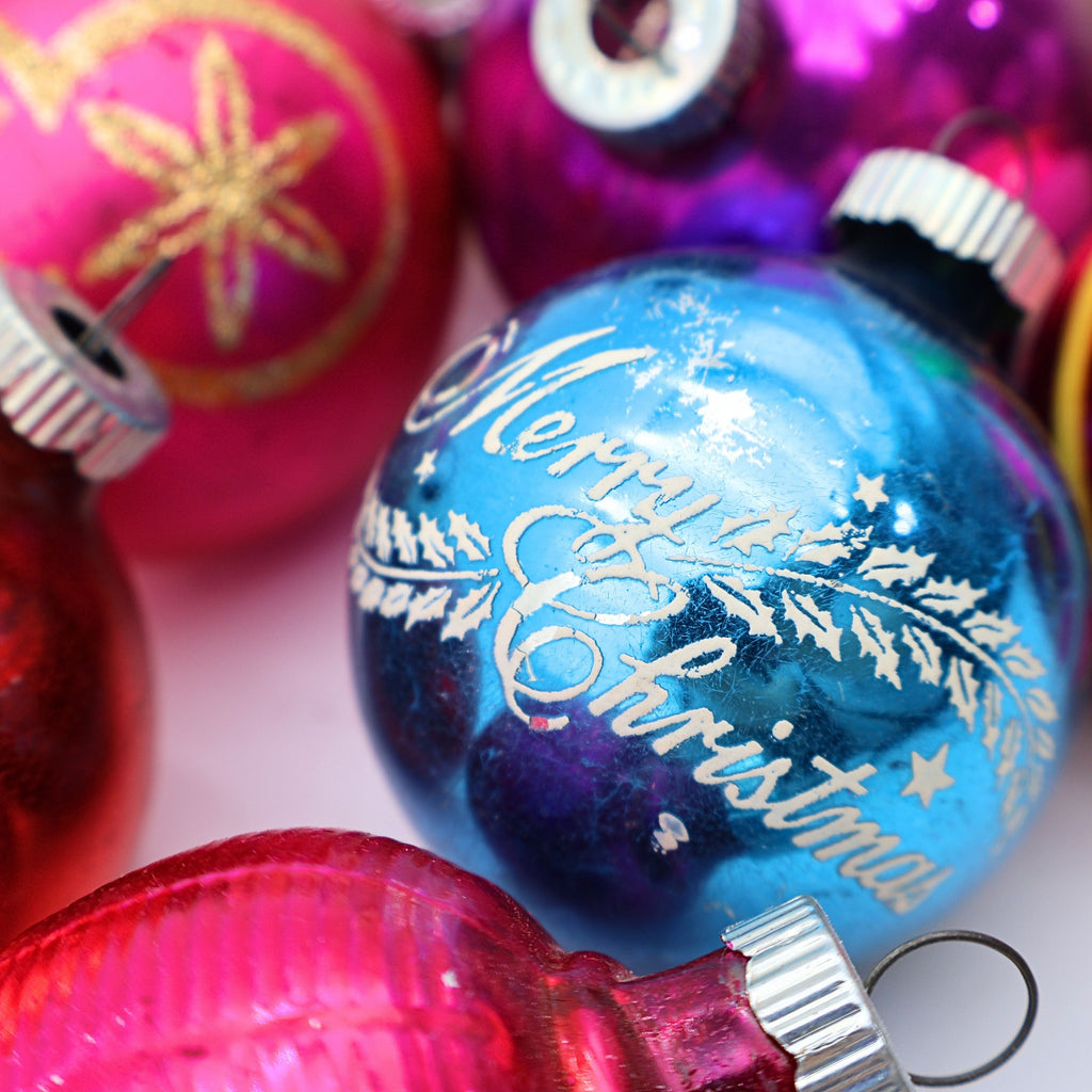 Closeup of vintage blue mercury glass Christmas ornament with colorful retro holiday baubles and jewel tone details