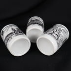 Low angled view of three vintage Bremen Germany porcelain shot glasses resting on their sides against black fabric. Their unmarked recessed bases are prominently visible, along with portions of the Roland, Rathaus, and Bremen Town Musicians landmark illustrations.