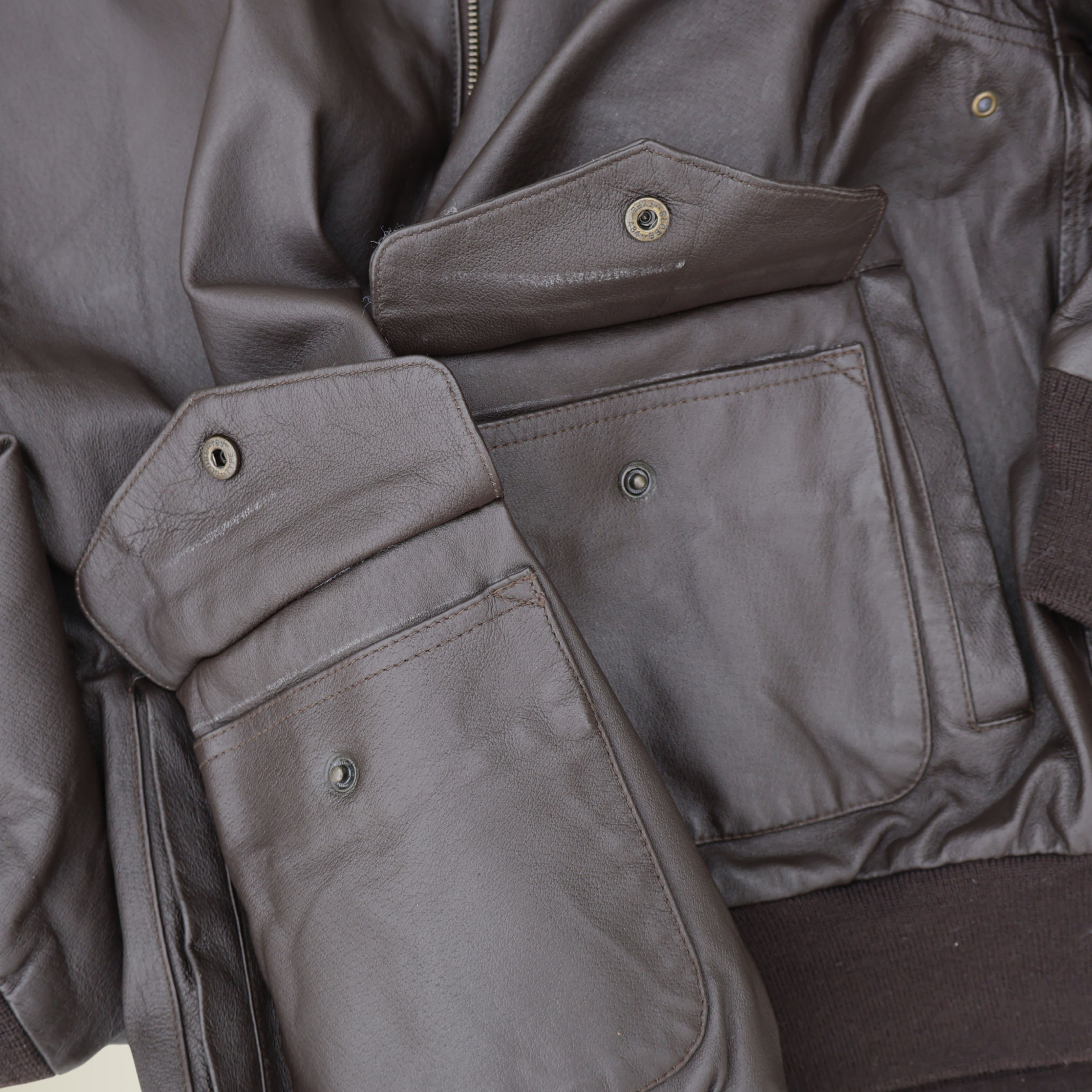 Close up of snap flap pocket on brown leather bomber jacket