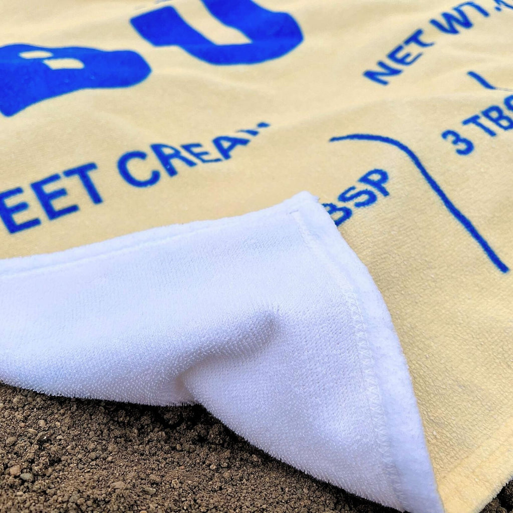 Close up of butter beach towel fabric showing soft texture and vibrant butter wrapper print. Absorbent and lightweight towel designed for comfort and style.