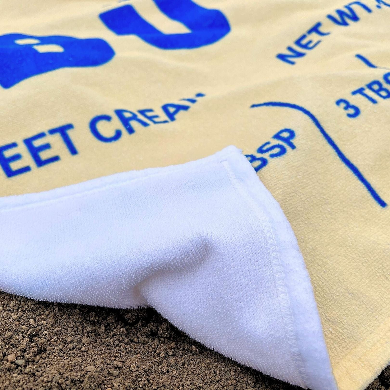 Close up of butter beach towel fabric showing soft texture and vibrant butter wrapper print. Absorbent and lightweight towel designed for comfort and style.