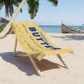 Butter beach towel styled on outdoor lounge chair in sunny vacation setting. Fun and eye catching towel perfect for summer travel, pool days, and beach lounging.