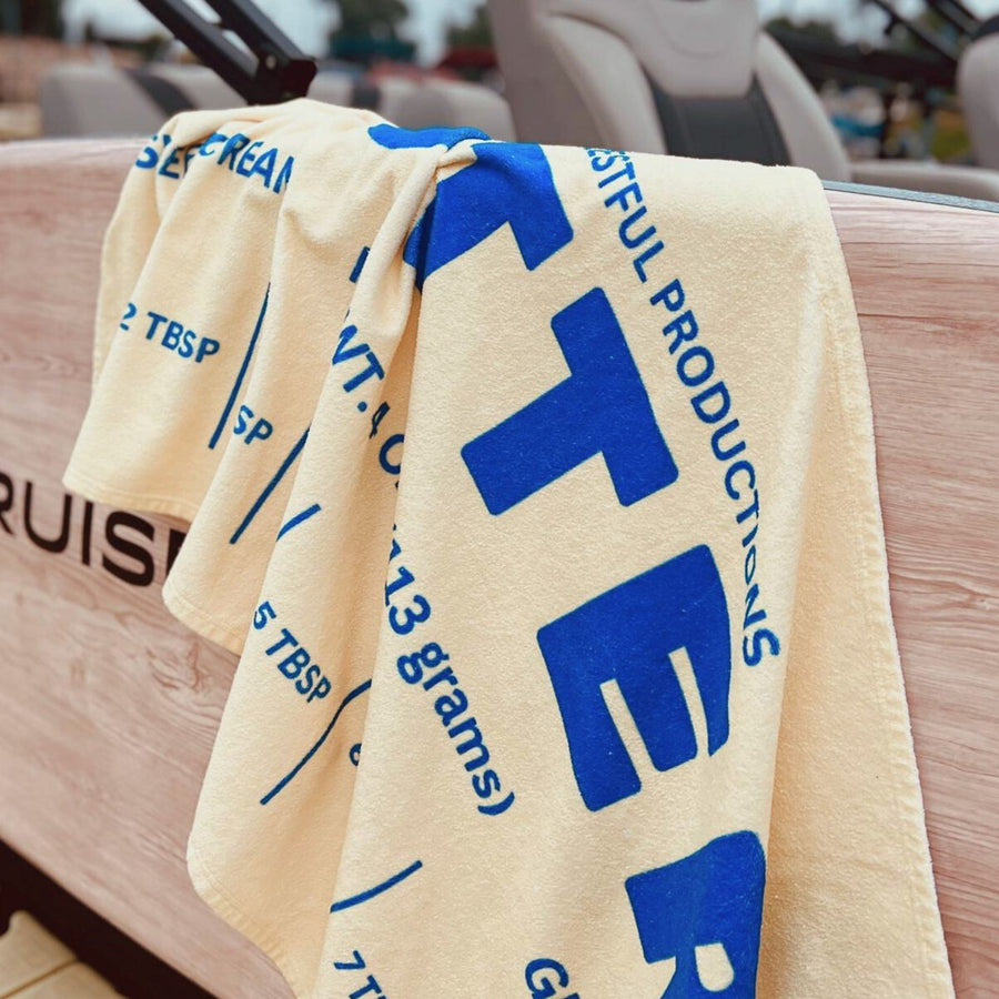 Butter beach towel with bold yellow butter wrapper design and blue typography. Funny pool towel perfect for summer vacations, beach trips, and unique gift ideas for butter lovers.