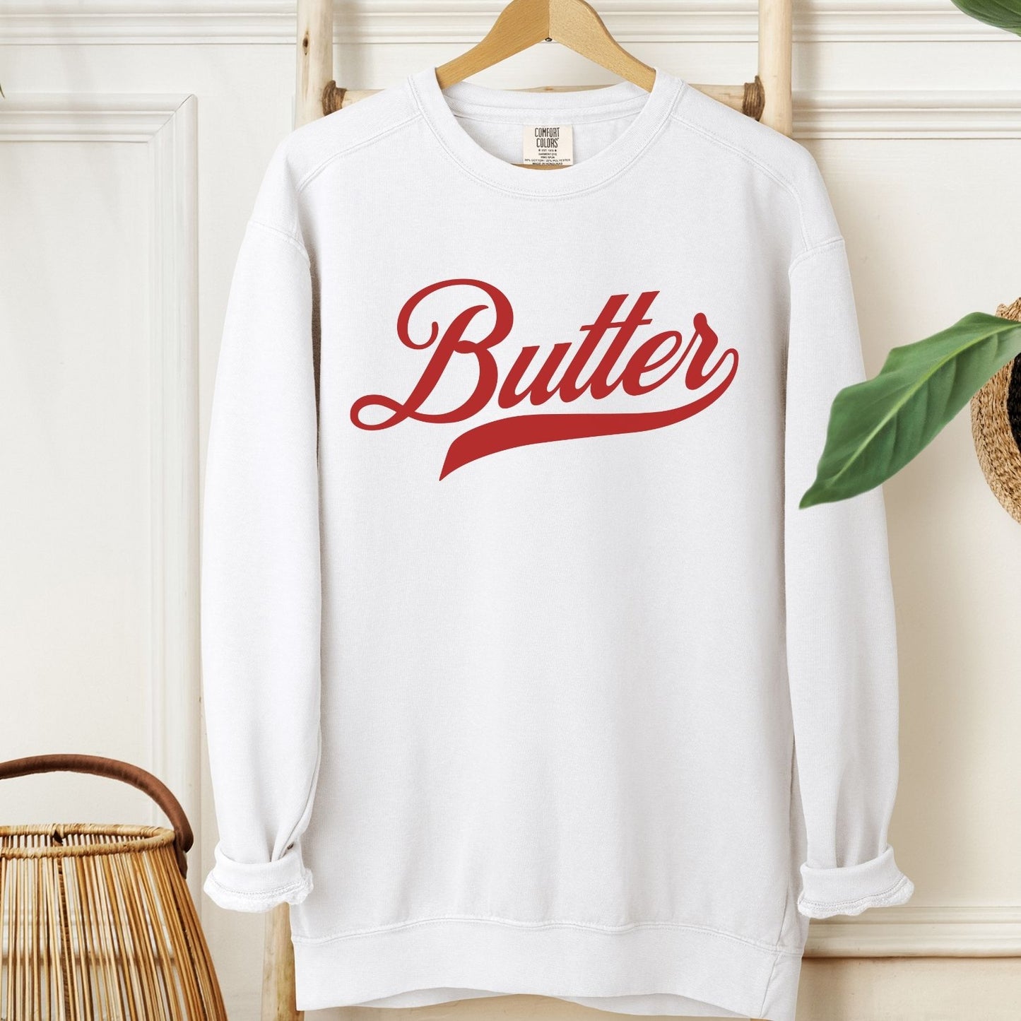 Butter script crewneck sweatshirt displayed on hanger in neutral setting. Vintage inspired graphic sweatshirt with bold lettering. Stylish and comfortable pullover for casual everyday outfits.