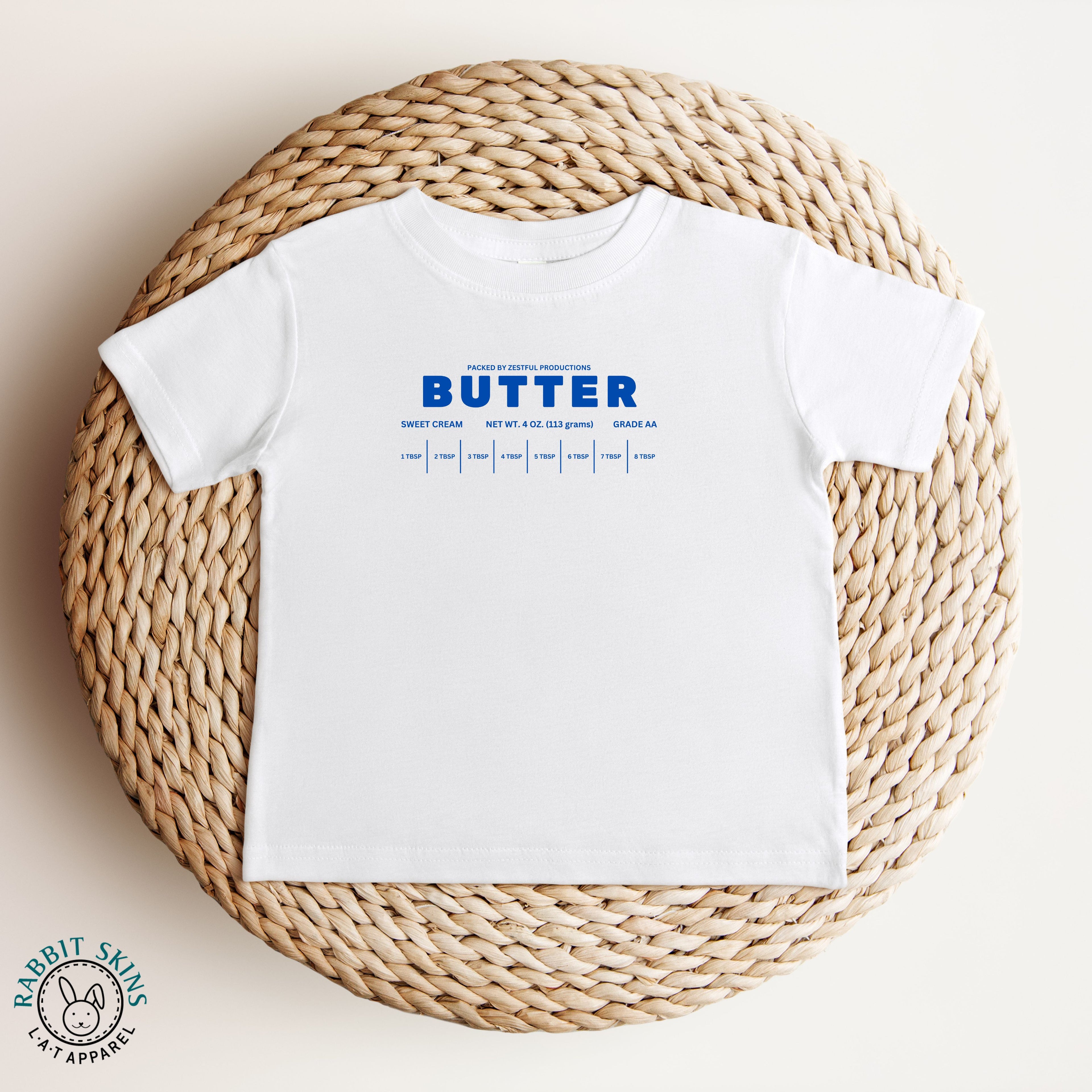 White butter infant tee shown in flat lay with clean graphic design. Soft cotton baby shirt perfect for layering and casual wear.