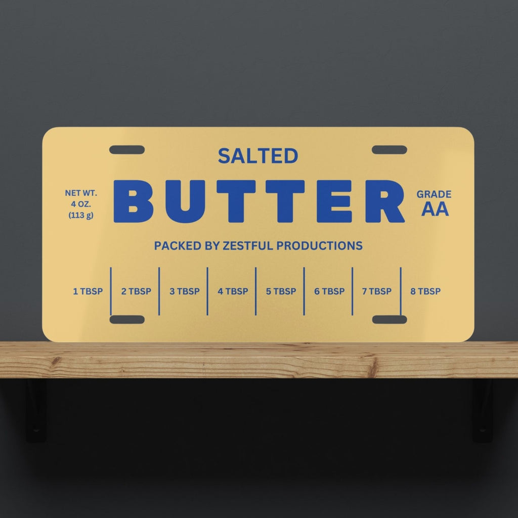Butter license plate displayed on shelf with bold butter stick design and blue lettering. Funny novelty decor piece for kitchens, offices, or gift giving.