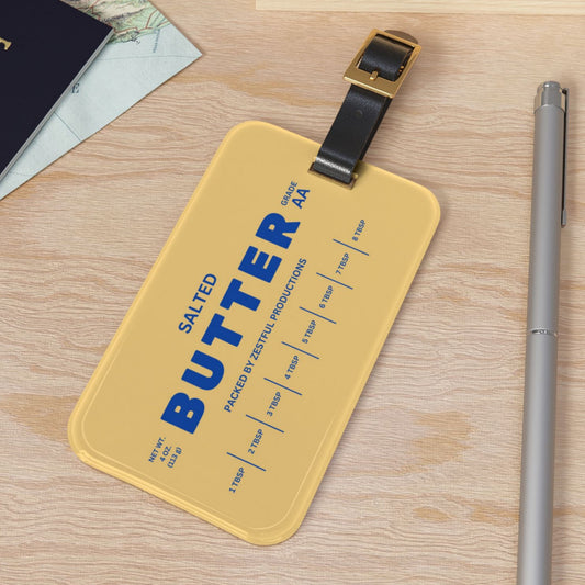 Butter luggage tag displayed on flat surface with strap and bold butter design. Stylish and functional travel tag for suitcases, backpacks, and carry-ons.