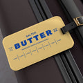 Butter luggage tag attached to suitcase with bold butter stick design and blue lettering. Funny travel accessory that makes bags easy to spot and adds personality to luggage.