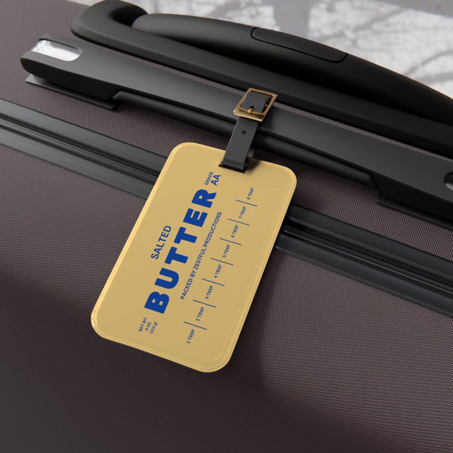 Butter luggage tag attached to suitcase handle in angled view. Durable and eye-catching travel accessory for easy bag identification at airports.