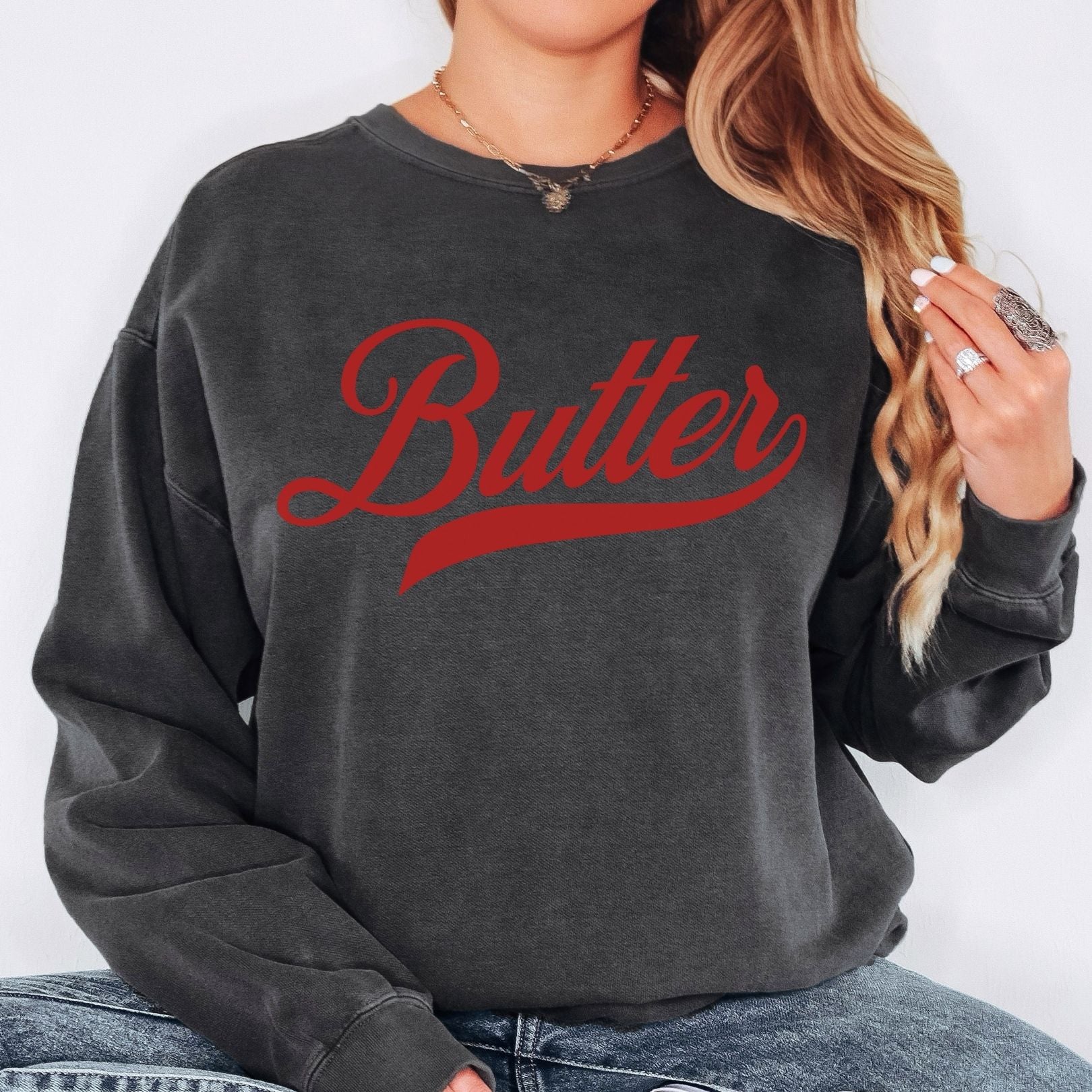 Black butter script crewneck sweatshirt styled in casual streetwear look. Bold vintage graphic pullover with relaxed fit. Ideal for everyday outfits and statement casual fashion.