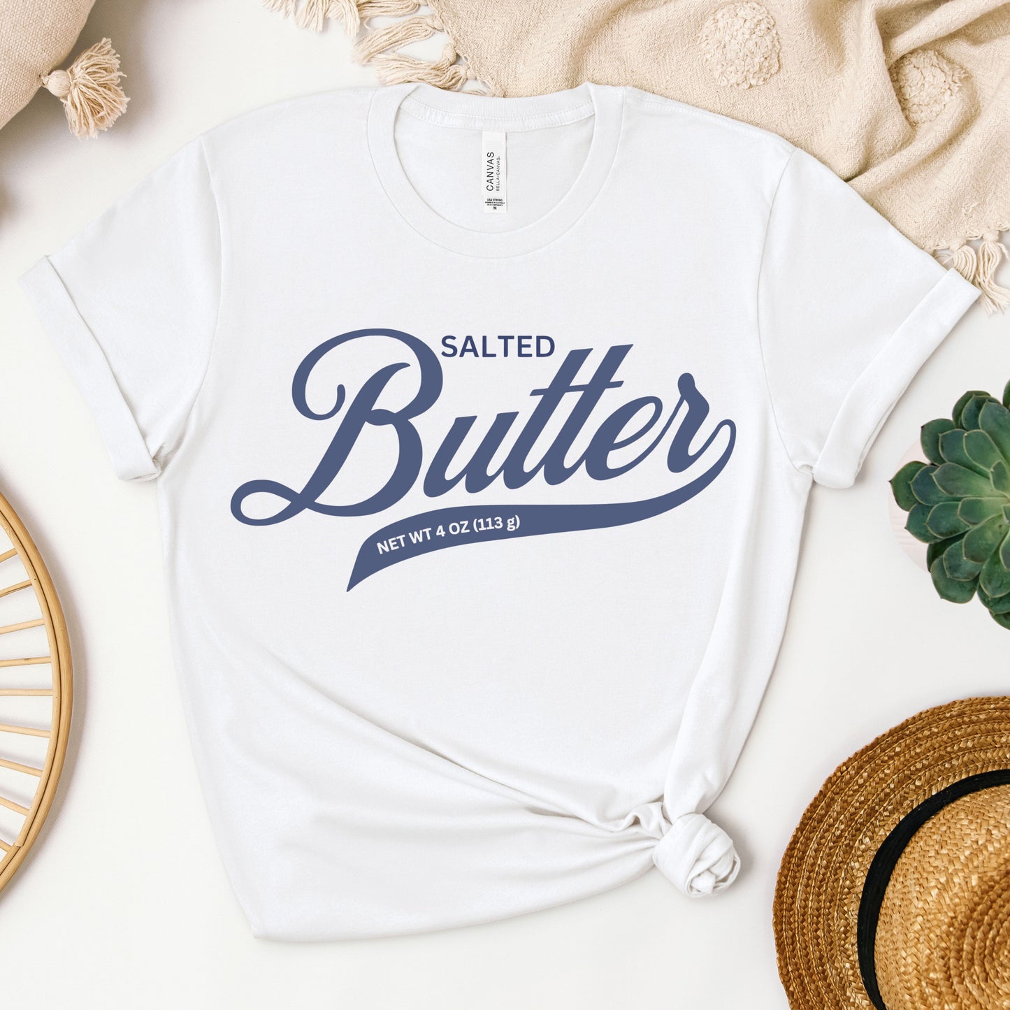 White butter script graphic tee shown in flat lay with clean bold lettering design. Soft cotton t shirt for everyday wear, gifting, and simple casual outfits.