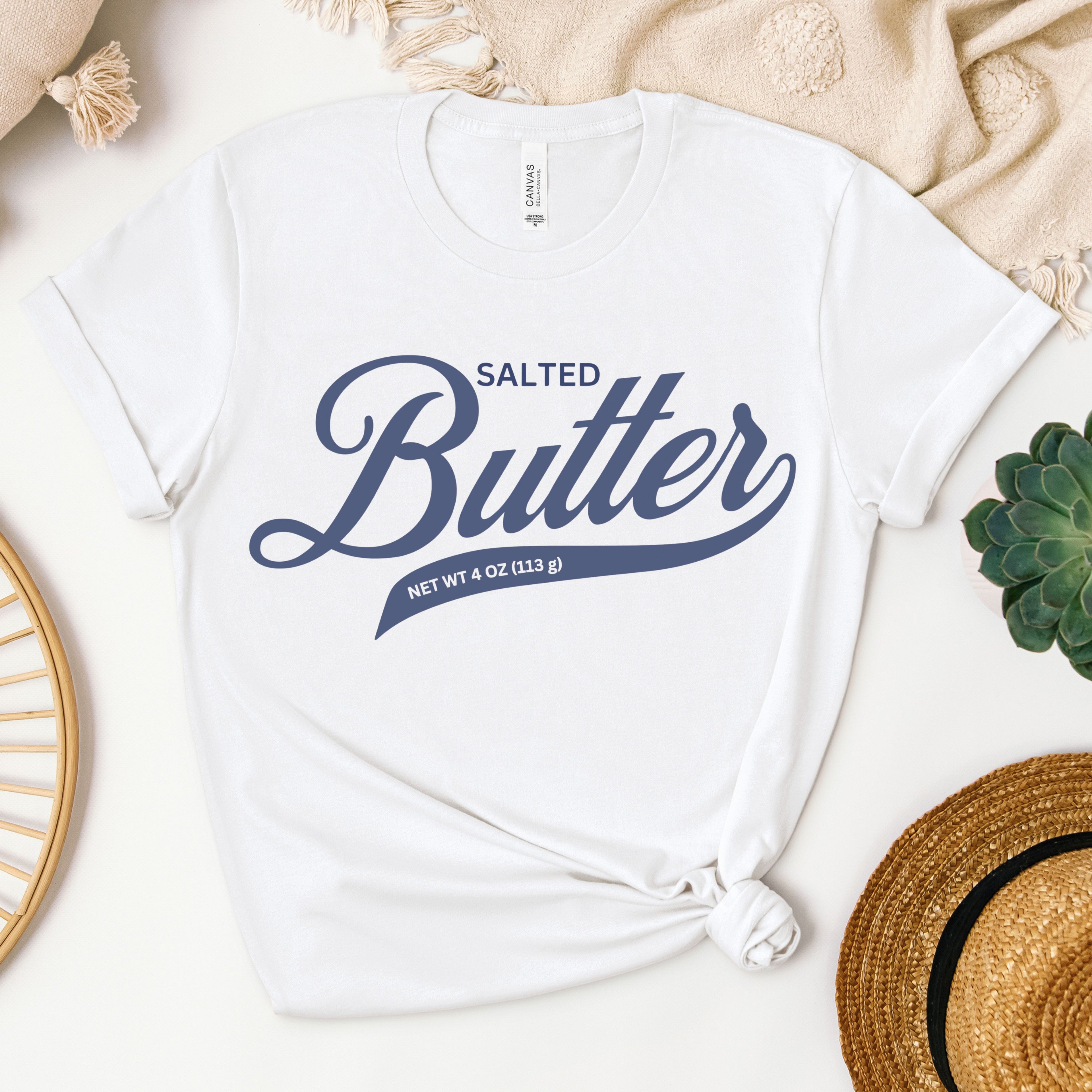 White butter script graphic tee shown in flat lay with clean bold lettering design. Soft cotton t shirt for everyday wear, gifting, and simple casual outfits.