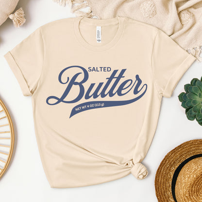 Neutral toned butter script graphic tee displayed in flat lay. Soft cotton shirt with bold lettering design perfect for layering and everyday casual style.