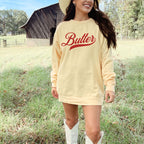 Yellow butter script sweatshirt worn in a relaxed outdoor setting. Vintage style crewneck with bold typography design. Soft and cozy graphic pullover ideal for casual outfits, gifting, and playful fashion lovers.