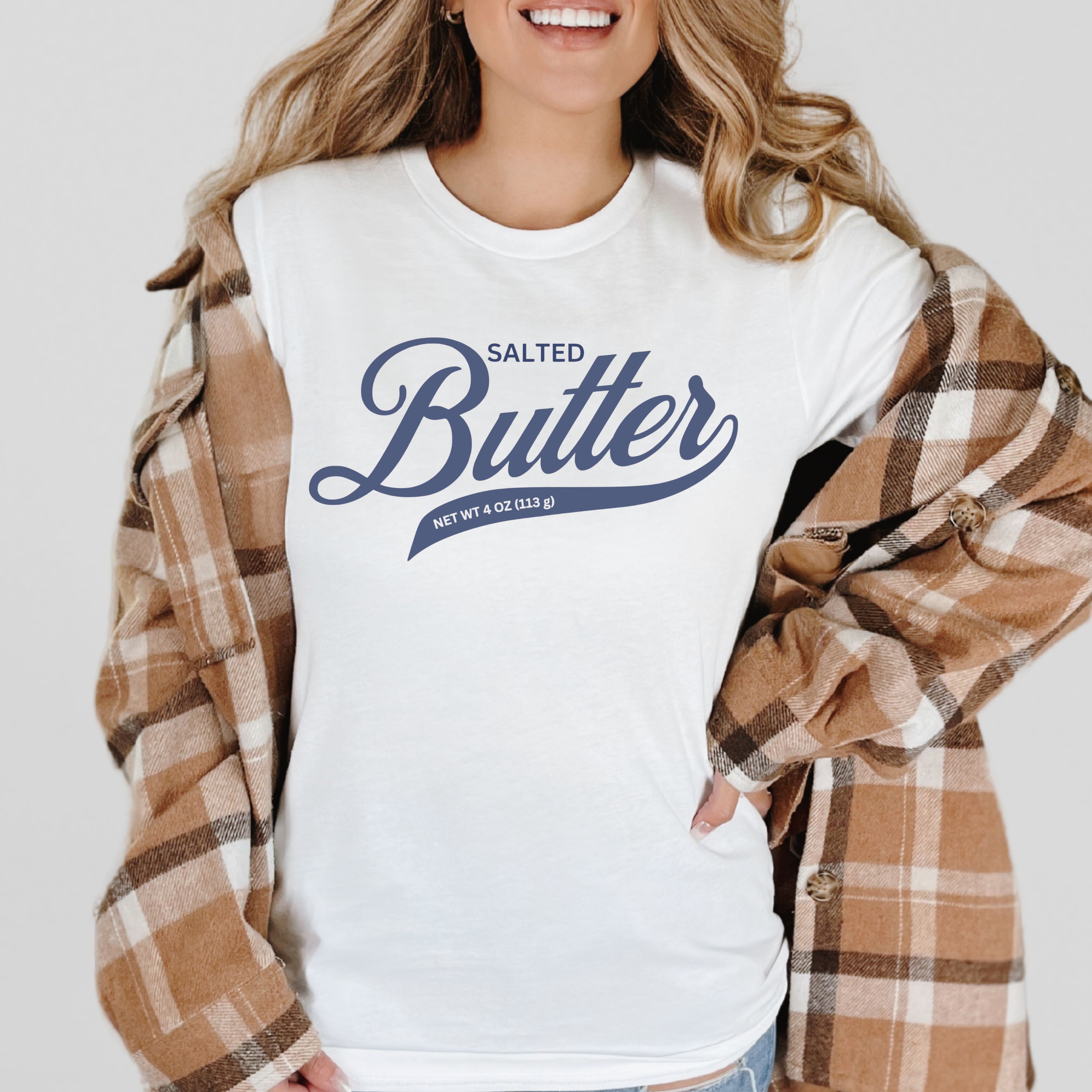 White butter script t shirt layered with flannel for casual outfit styling. Comfortable graphic tee with clean script design for everyday wear.