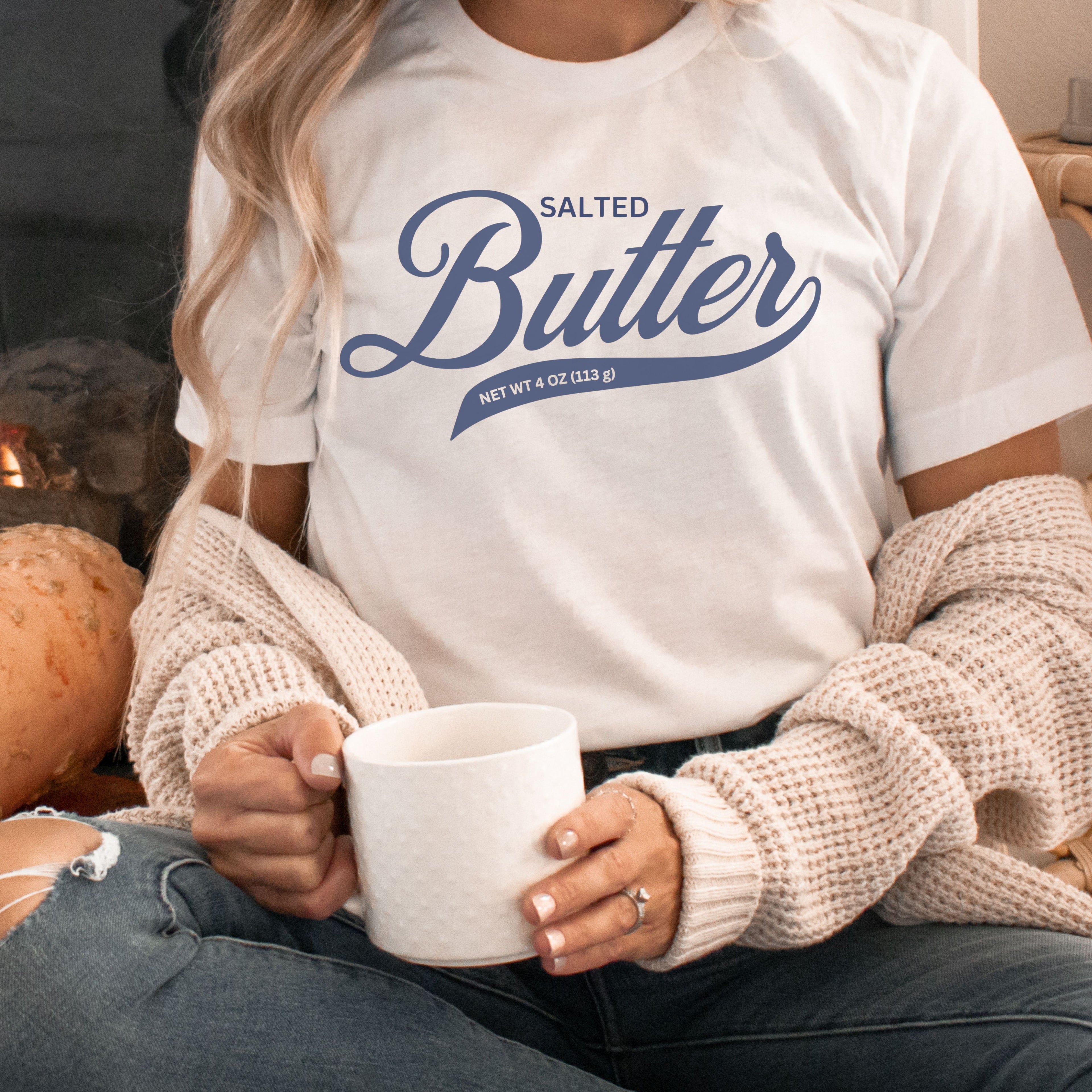 Butter script graphic tee in white color styled with cozy outfit and coffee mug. Comfortable cotton t shirt with bold script lettering perfect for casual wear and butter lovers.