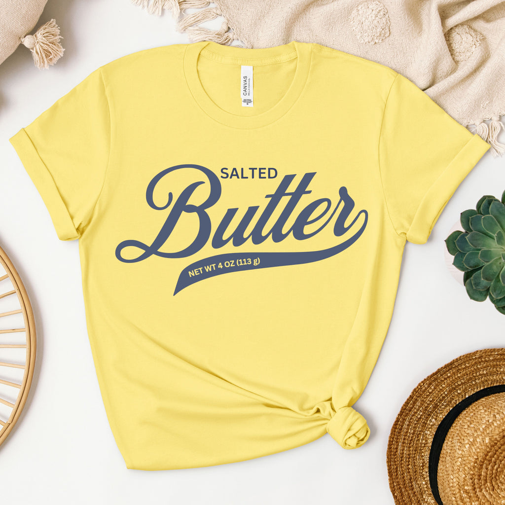 Yellow butter script graphic tee flat lay with bright bold lettering. Fun and eye catching t shirt for summer outfits, casual wear, and playful fashion lovers.