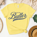 Yellow butter script graphic tee flat lay with bright bold lettering. Fun and eye catching t shirt for summer outfits, casual wear, and playful fashion lovers.