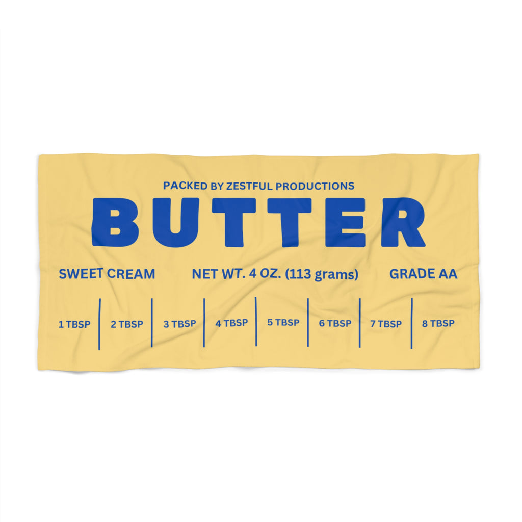 Butter wrapper graphic detail on beach towel with bold blue lettering and measurement markings. Unique novelty design inspired by classic butter packaging.